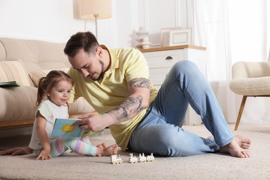 Photo of Happy family. Father and his cute little daughter reading book at home