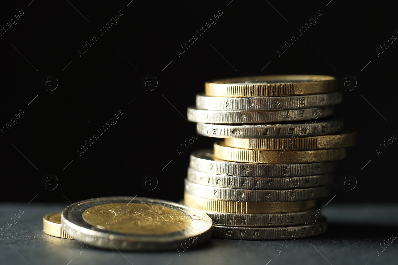 Photo of Stacked euro coins on grey table, closeup