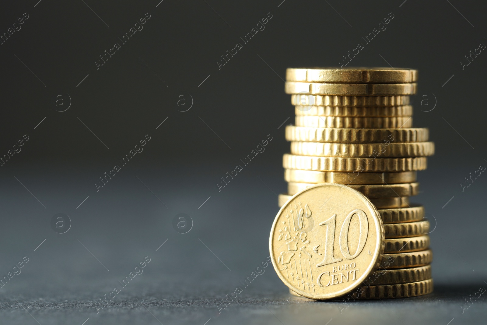 Photo of Stacked euro coins on grey table, space for text