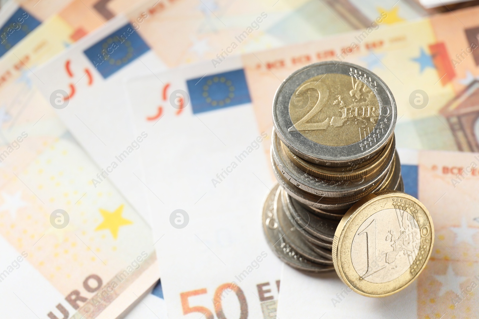 Photo of Stack of coins on euro banknotes, closeup. Space for text