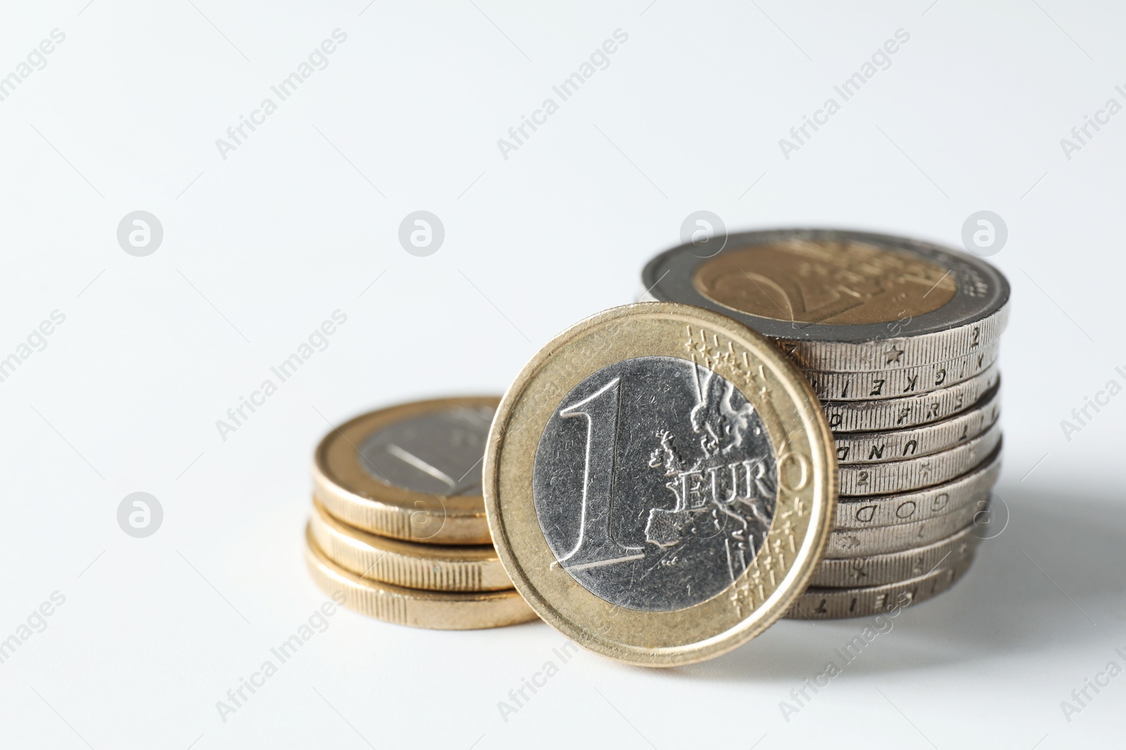 Photo of Stacked euro coins on white background, closeup