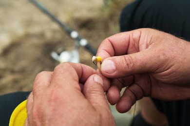 Senior fisherman holding fishing equipment outdoors, closeup