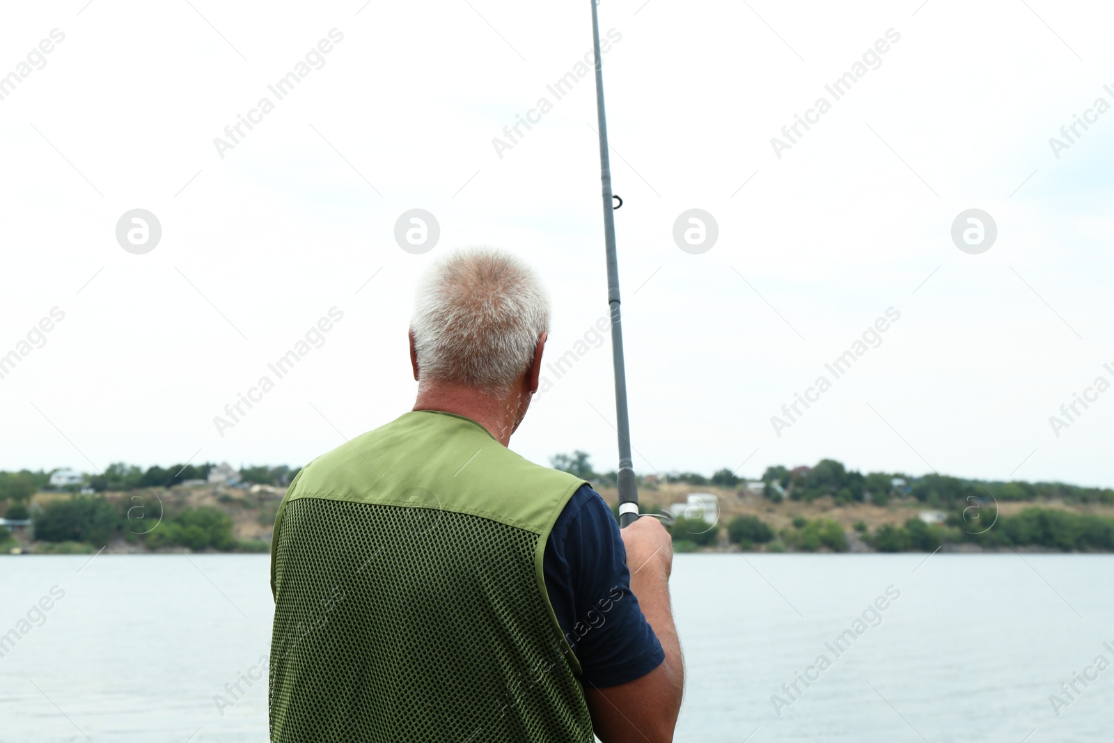 Photo of Fisherman with rod fishing near lake at summer