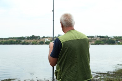 Photo of Fisherman with rod fishing near lake at summer