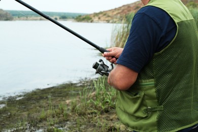 Photo of Fisherman with rod fishing near lake at summer, closeup