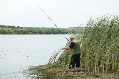 Photo of Fisherman with rod fishing near lake at summer