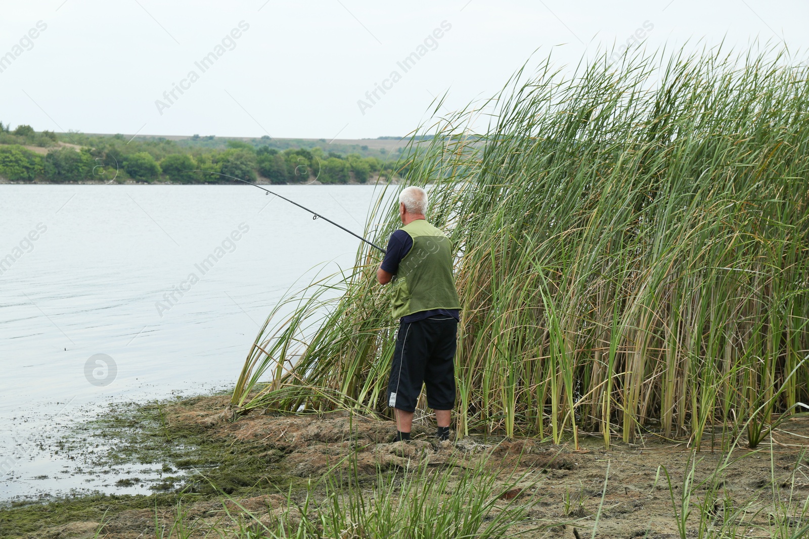 Photo of Fisherman with rod fishing near lake at summer