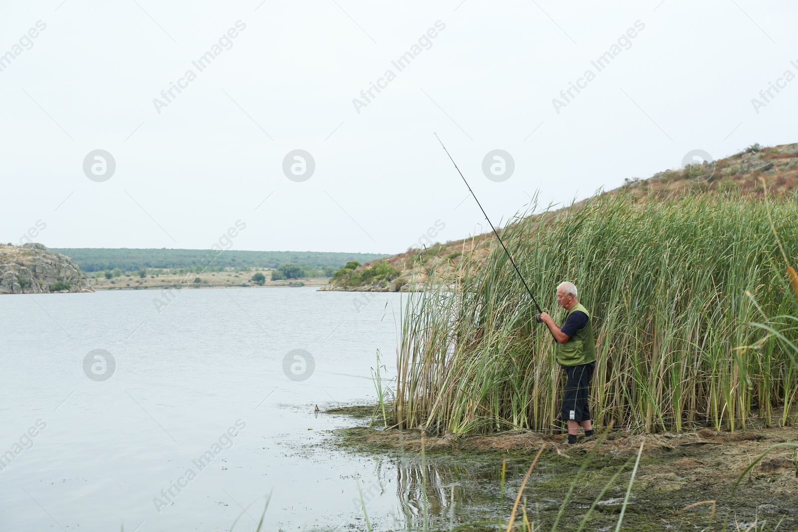 Photo of Fisherman with rod fishing near lake at summer