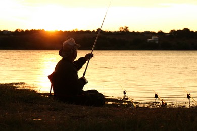 Fisherman with rod fishing near lake at sunset. Space for text