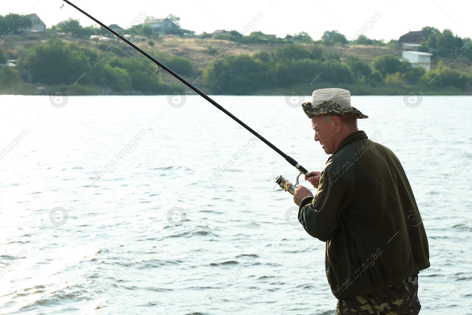 Photo of Fisherman with rod fishing near lake at summer