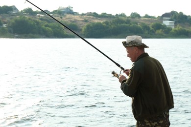 Photo of Fisherman with rod fishing near lake at summer