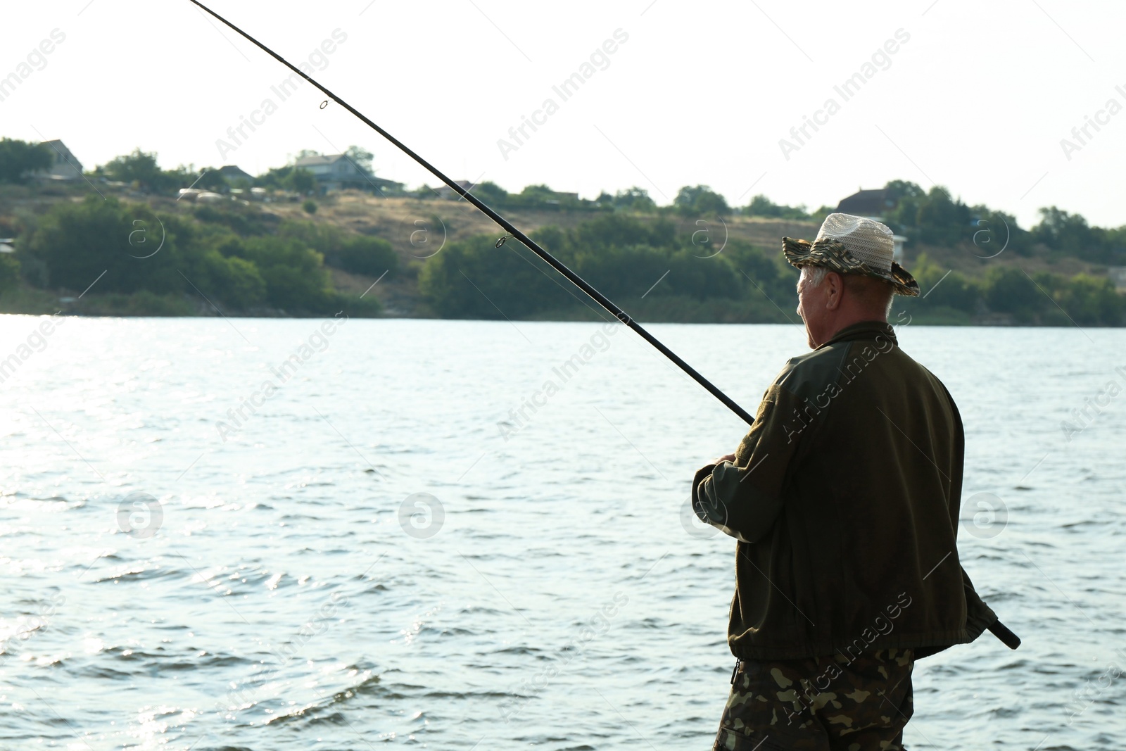 Photo of Fisherman with rod fishing near lake at summer