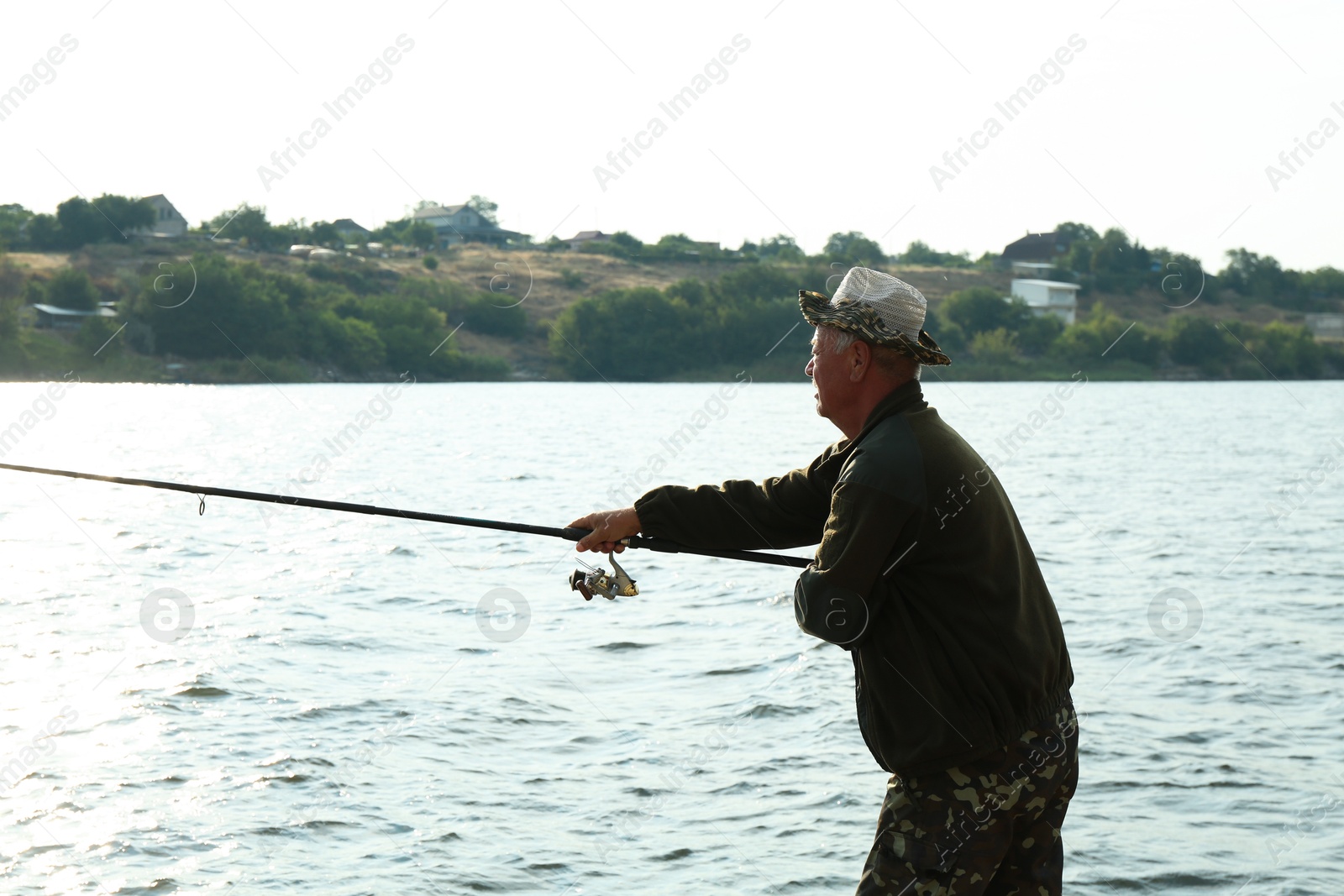 Photo of Fisherman with rod fishing near lake at summer