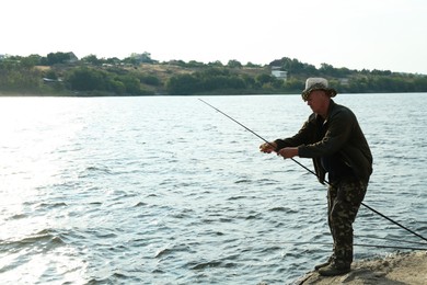 Fisherman with rod fishing near lake at summer, space for text