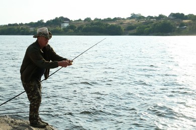 Photo of Fisherman with rod fishing near lake at summer, space for text