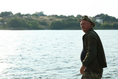 Photo of Fisherman with rod fishing near lake at summer, space for text