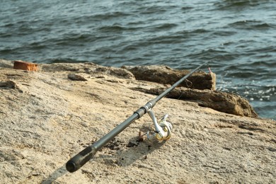 One fishing rod on shore near lake outdoors