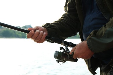 Fisherman with rod fishing near lake at summer, closeup