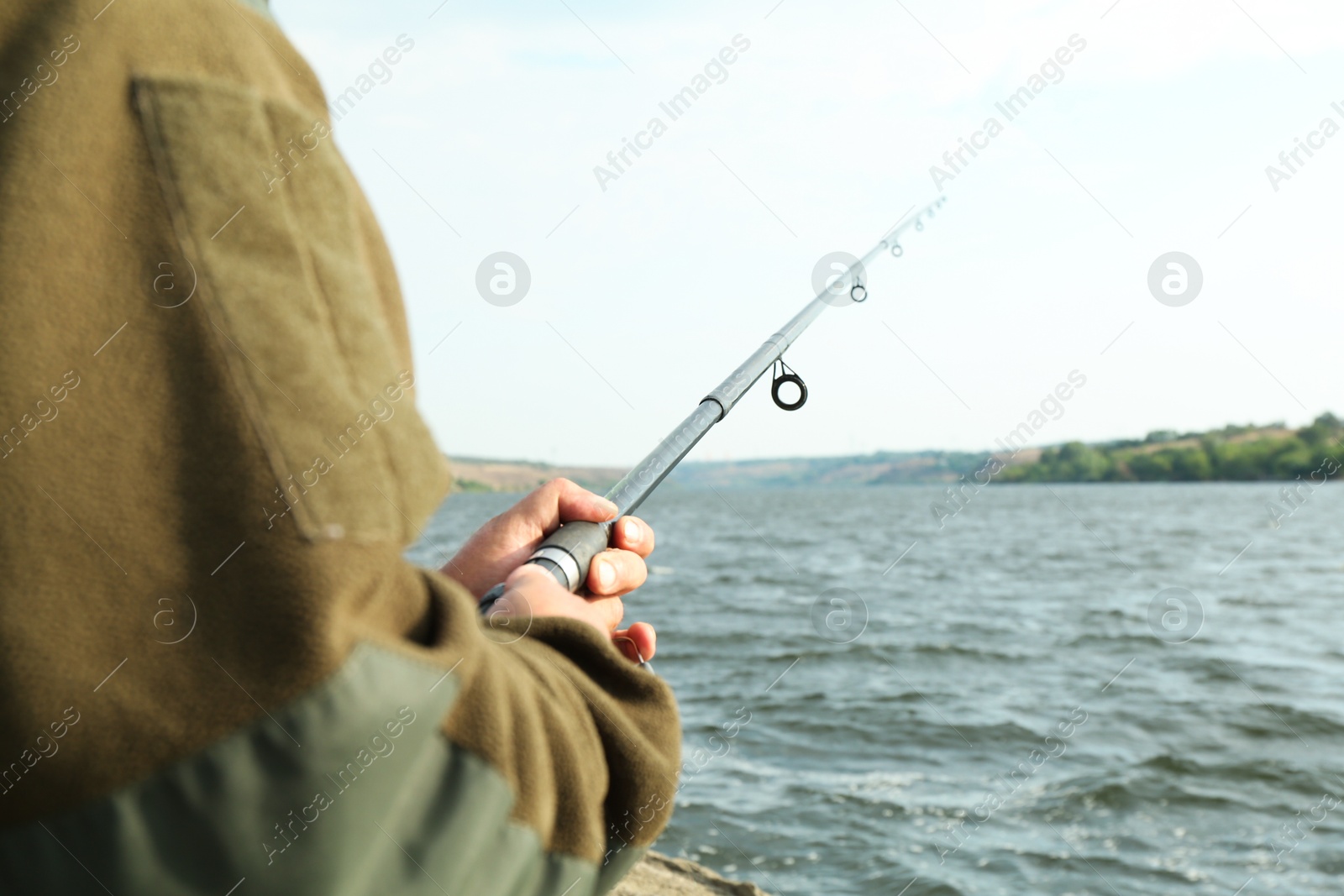 Photo of Fisherman with rod fishing near lake at summer, closeup