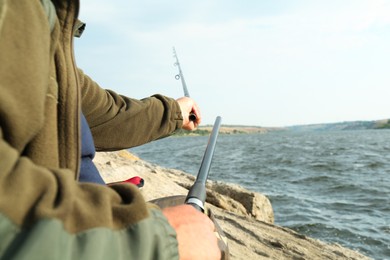 Fisherman with rod fishing near lake at summer, closeup