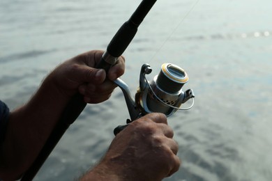 Fisherman with rod fishing near lake at summer, closeup