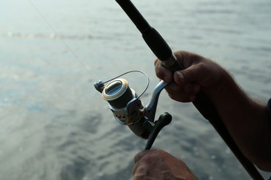 Photo of Fisherman with rod fishing near lake at summer, closeup