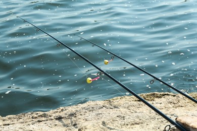 Photo of Two fishing rods on shore near lake outdoors