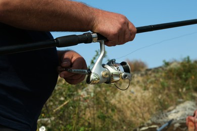 Fisherman with rod fishing near lake at summer, closeup