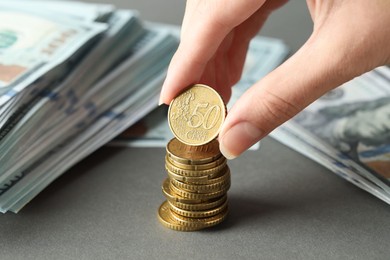 Photo of Woman stacking coins at grey table, closeup