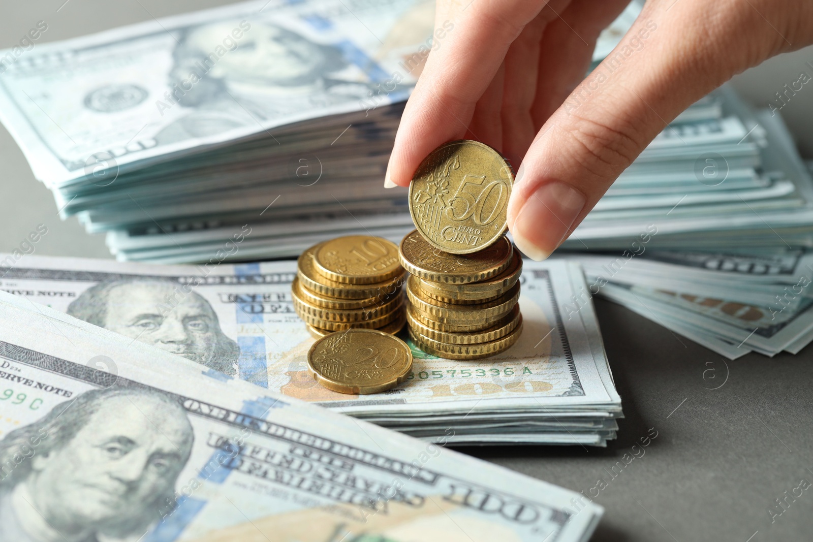 Photo of Woman stacking coins at grey table, closeup