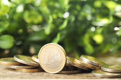 Photo of Many euro coins on wooden table outdoors