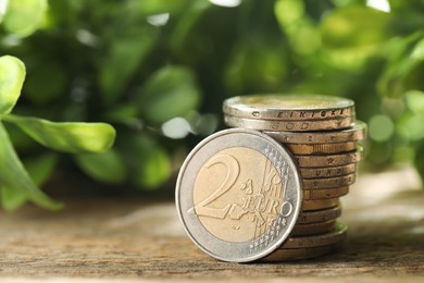 Photo of Stacked euro coins on wooden table outdoors, closeup