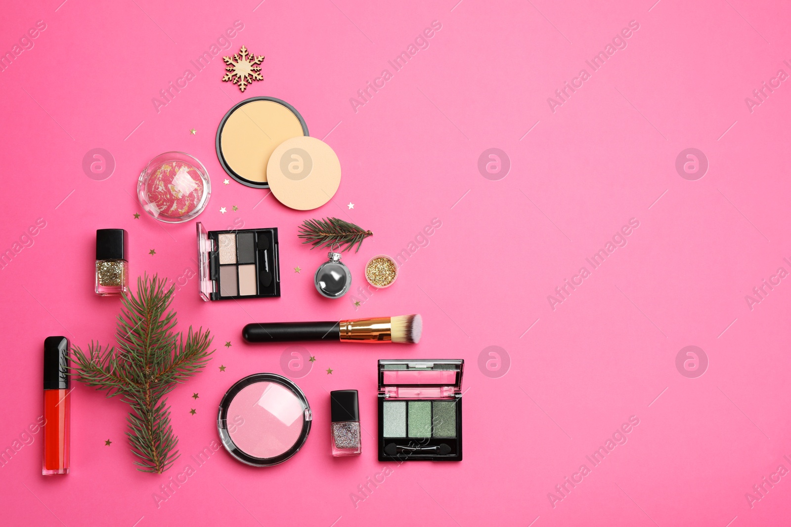 Photo of Flat lay composition with makeup products and Christmas decor on pink background. Space for text