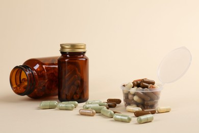 Pharmacist. Many different pills in plastic container and bottles on beige background