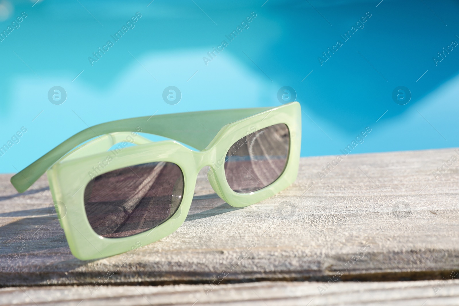 Photo of Stylish sunglasses on wooden surface, closeup. Beach accessory