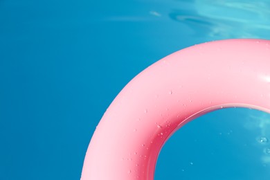 Photo of Pink inflatable ring in swimming pool outdoors, closeup