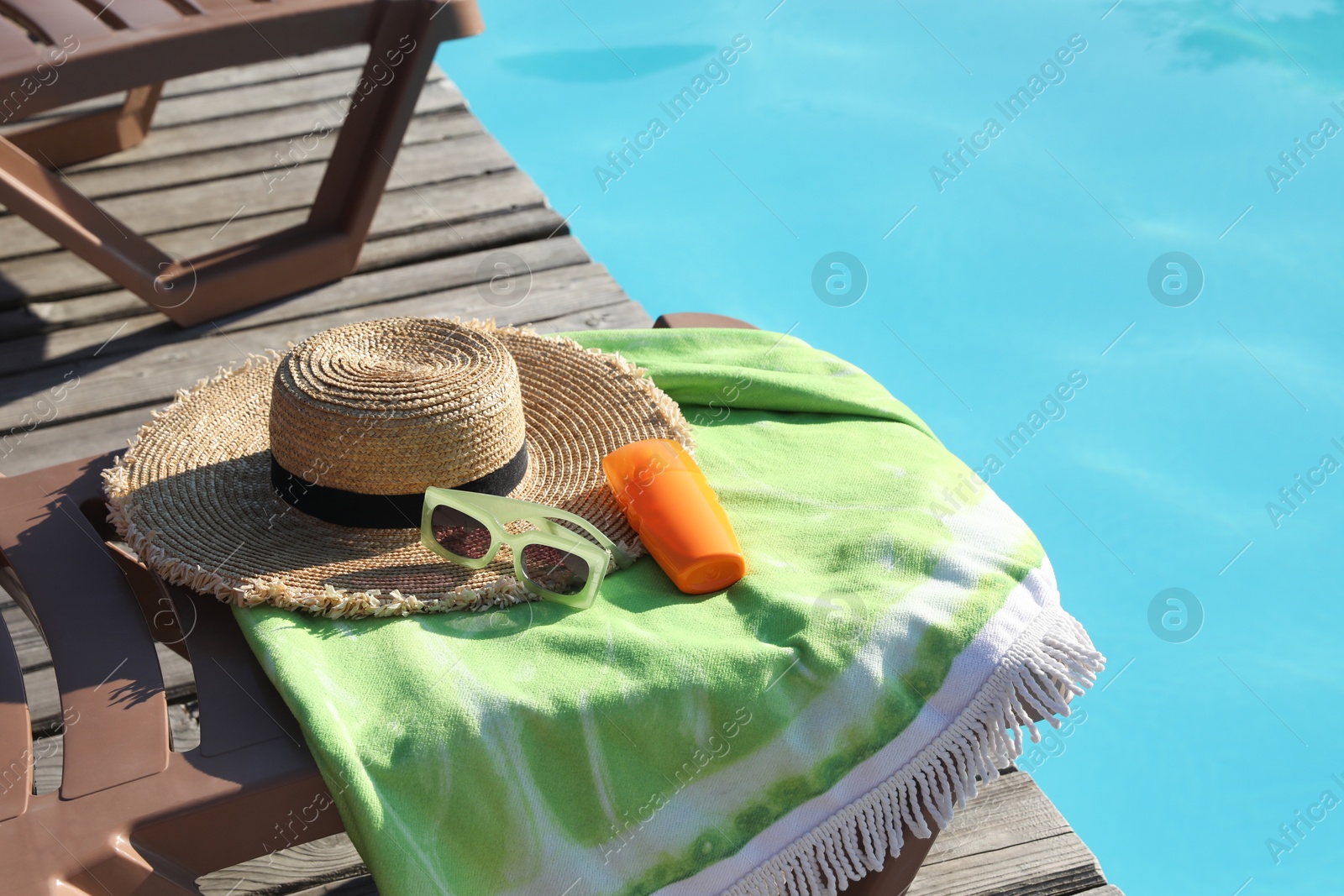 Photo of Beach accessories and sun loungers on wooden deck near outdoor swimming pool