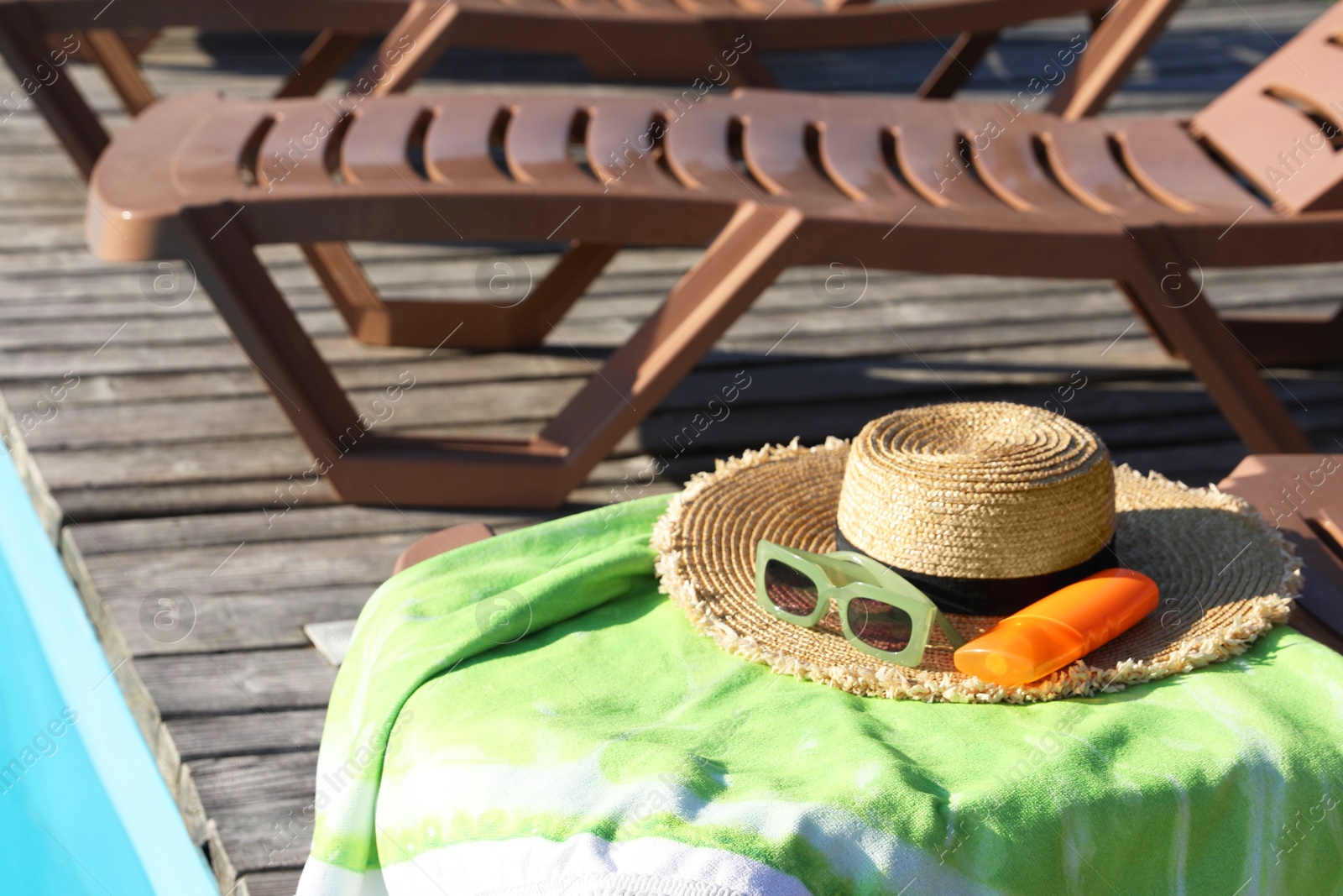 Photo of Beach accessories and sun loungers on wooden deck near outdoor swimming pool