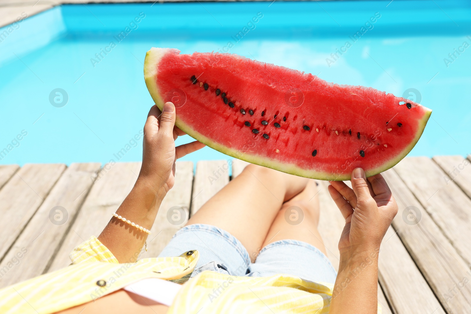 Photo of Woman with slice of juicy watermelon near swimming pool outdoors, closeup