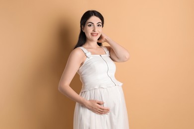 Photo of Portrait of beautiful pregnant woman on beige background