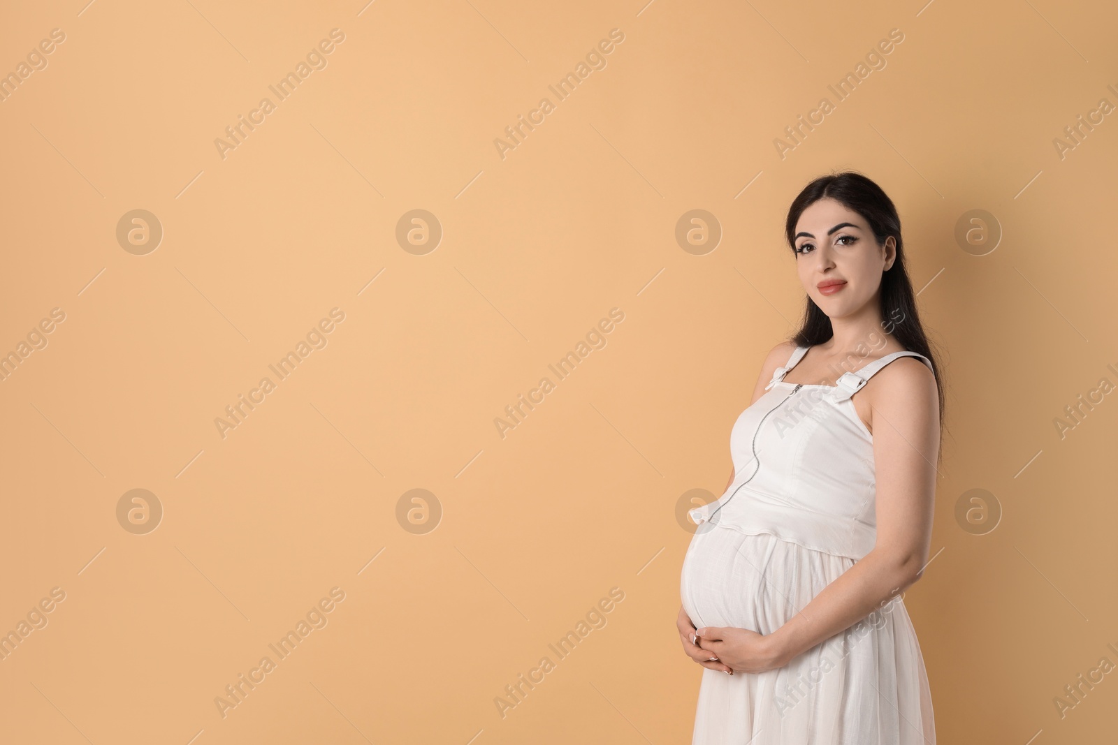 Photo of Portrait of beautiful pregnant woman on beige background, space for text