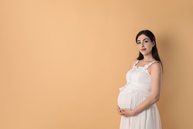 Photo of Portrait of beautiful pregnant woman on beige background, space for text