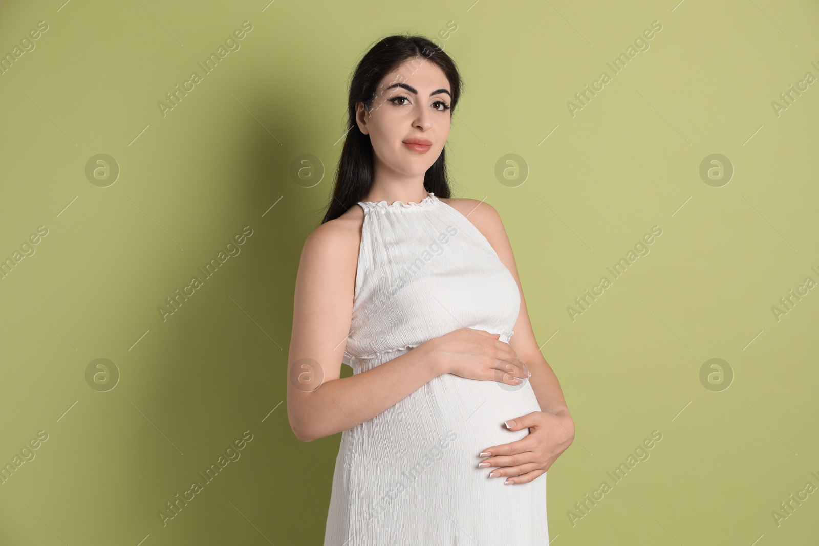 Photo of Portrait of beautiful pregnant woman on light olive background