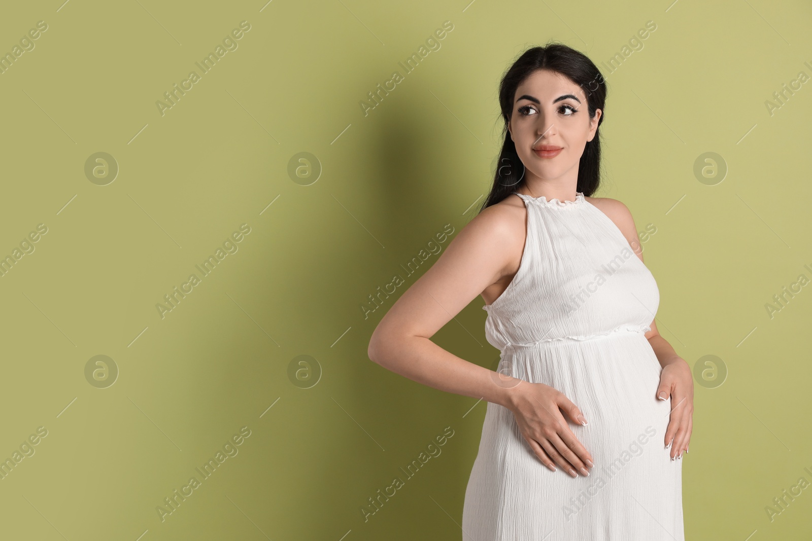 Photo of Portrait of beautiful pregnant woman on light olive background, space for text