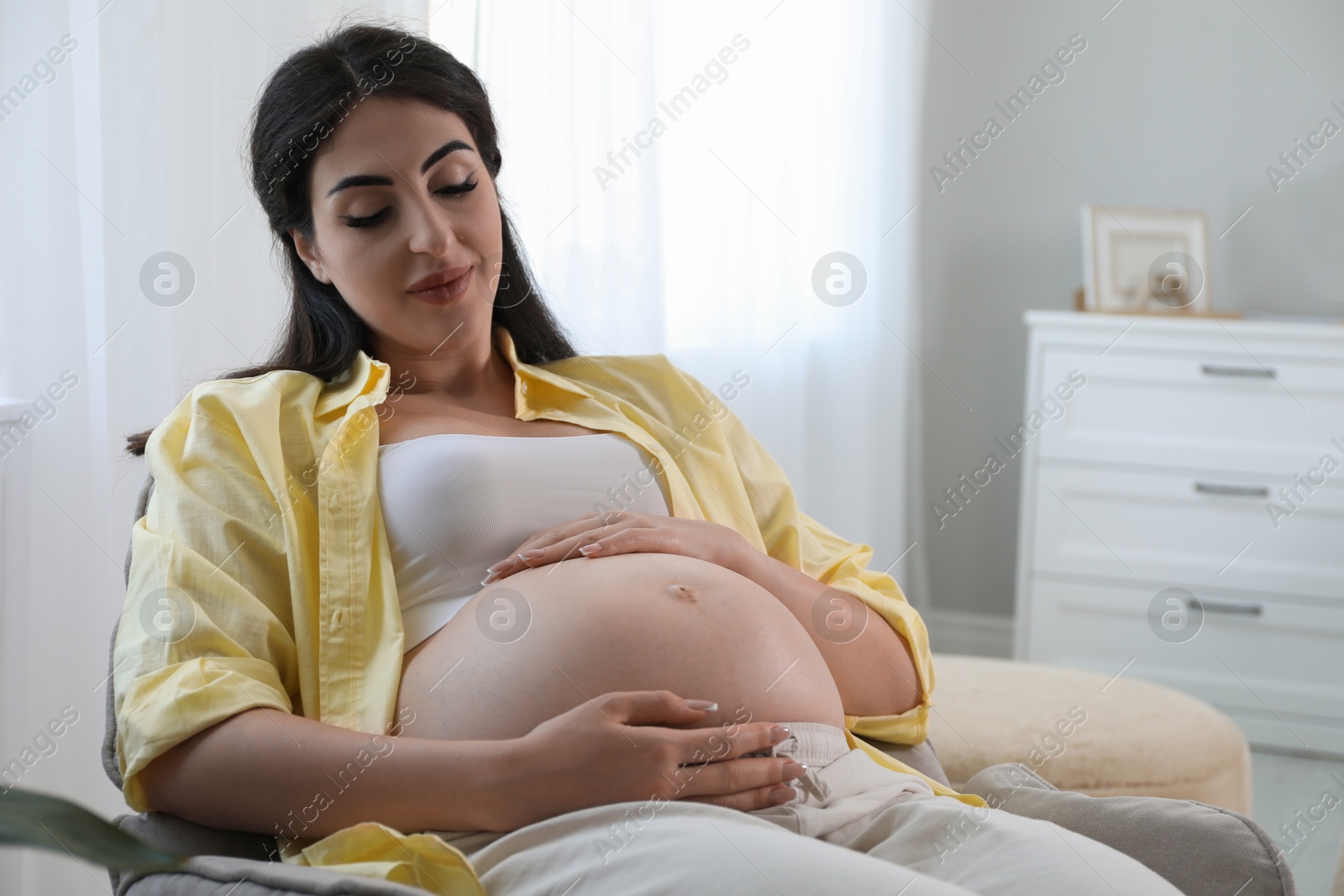 Photo of Young pregnant woman lying on bed at home