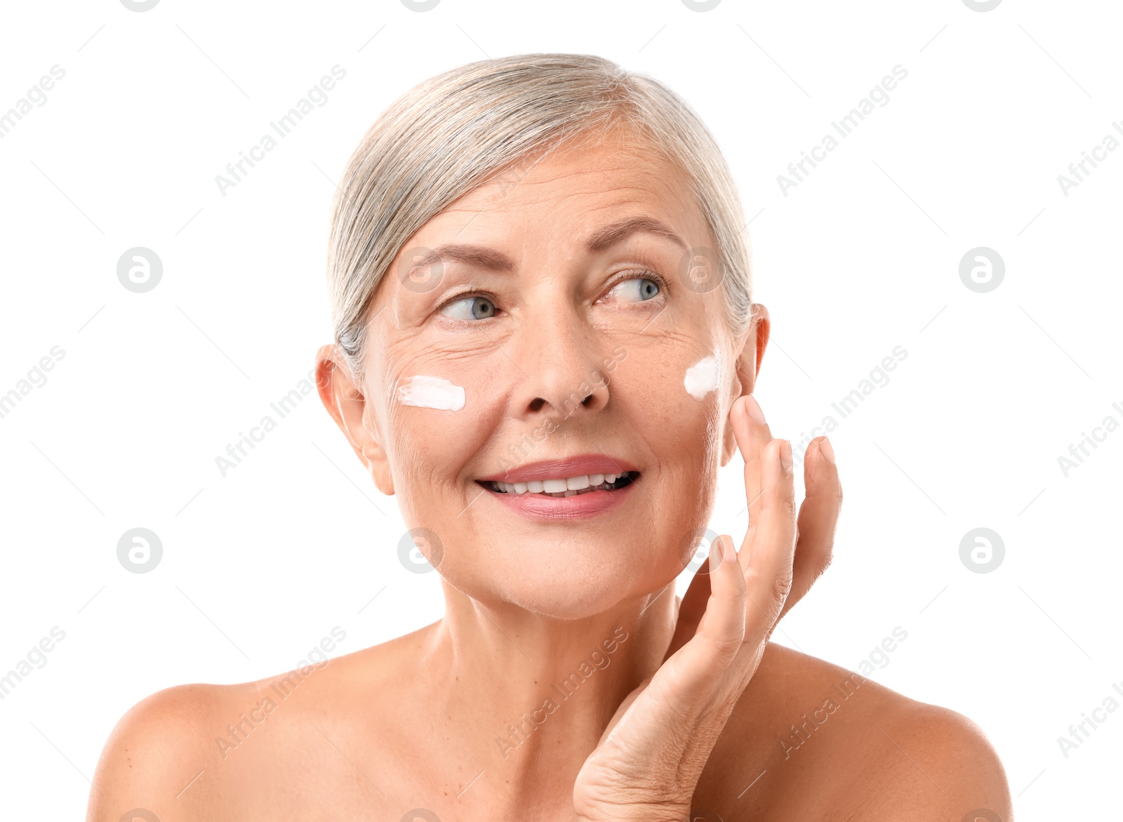 Photo of Senior woman applying face cream on white background