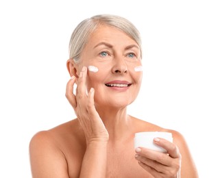 Senior woman applying face cream on white background