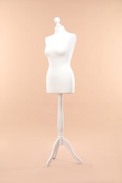 One female mannequin on stand against beige background