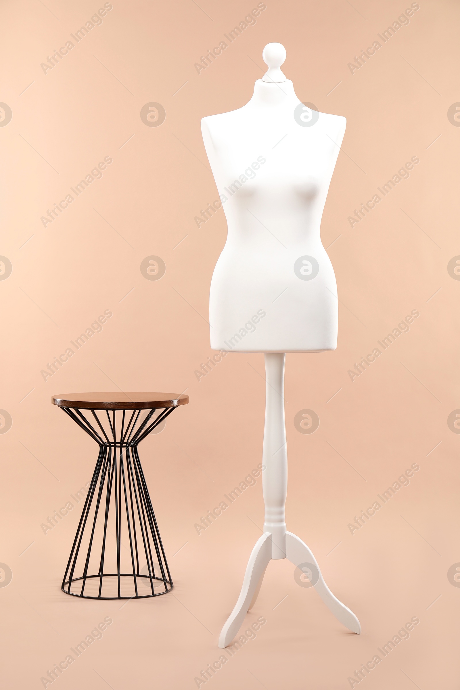 Photo of One female mannequin on stand and coffee table against beige background