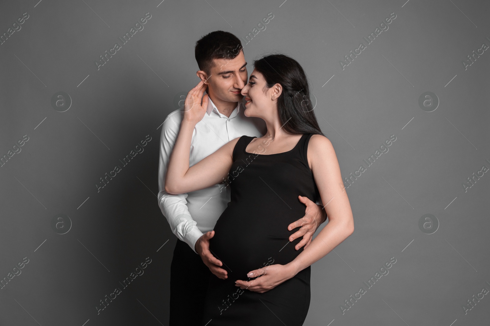 Photo of Beautiful pregnant woman with her husband on grey background